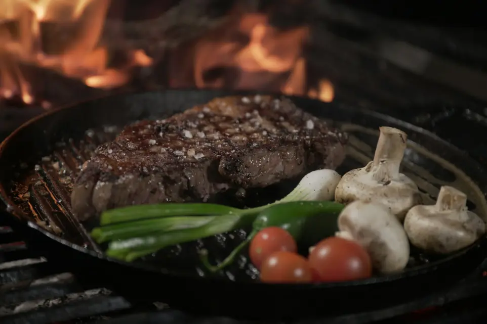 a steak and vegetables cooking on a grill